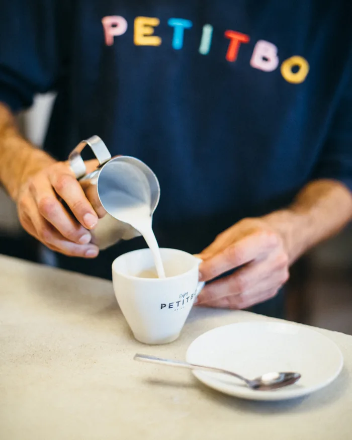 Barista sirviendo leche con la camiseta de Petitbo
