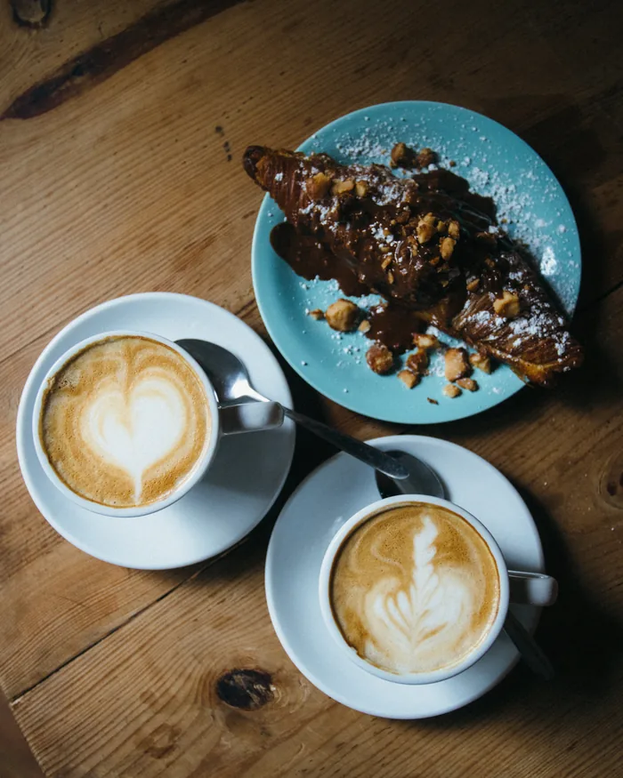 Cafés con arte latte y croissant de chocolate