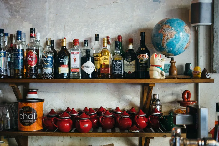 La estantería de la barra: botellas, teteras rojas y el globo